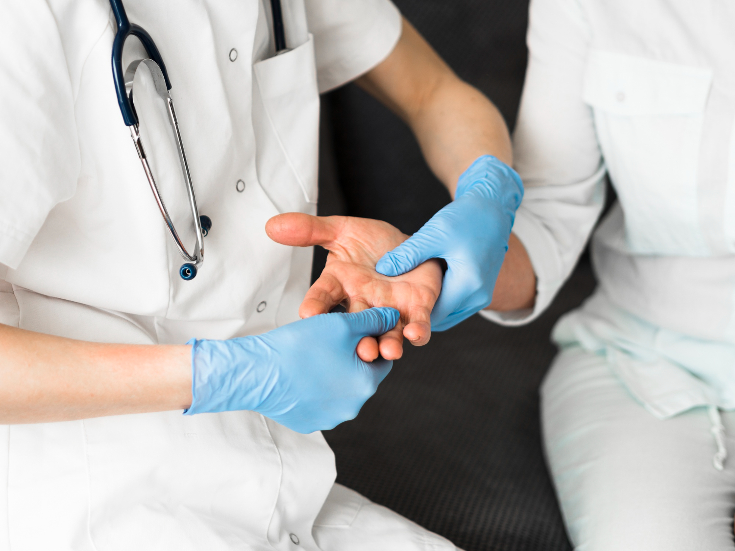 Gloved healthcare professional examining a patient's hand