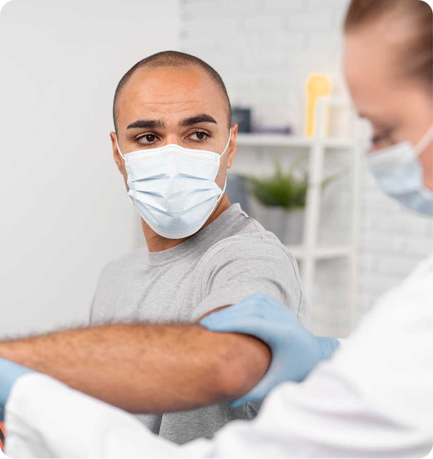 Gloved clinician examining a masked patient’s elbow