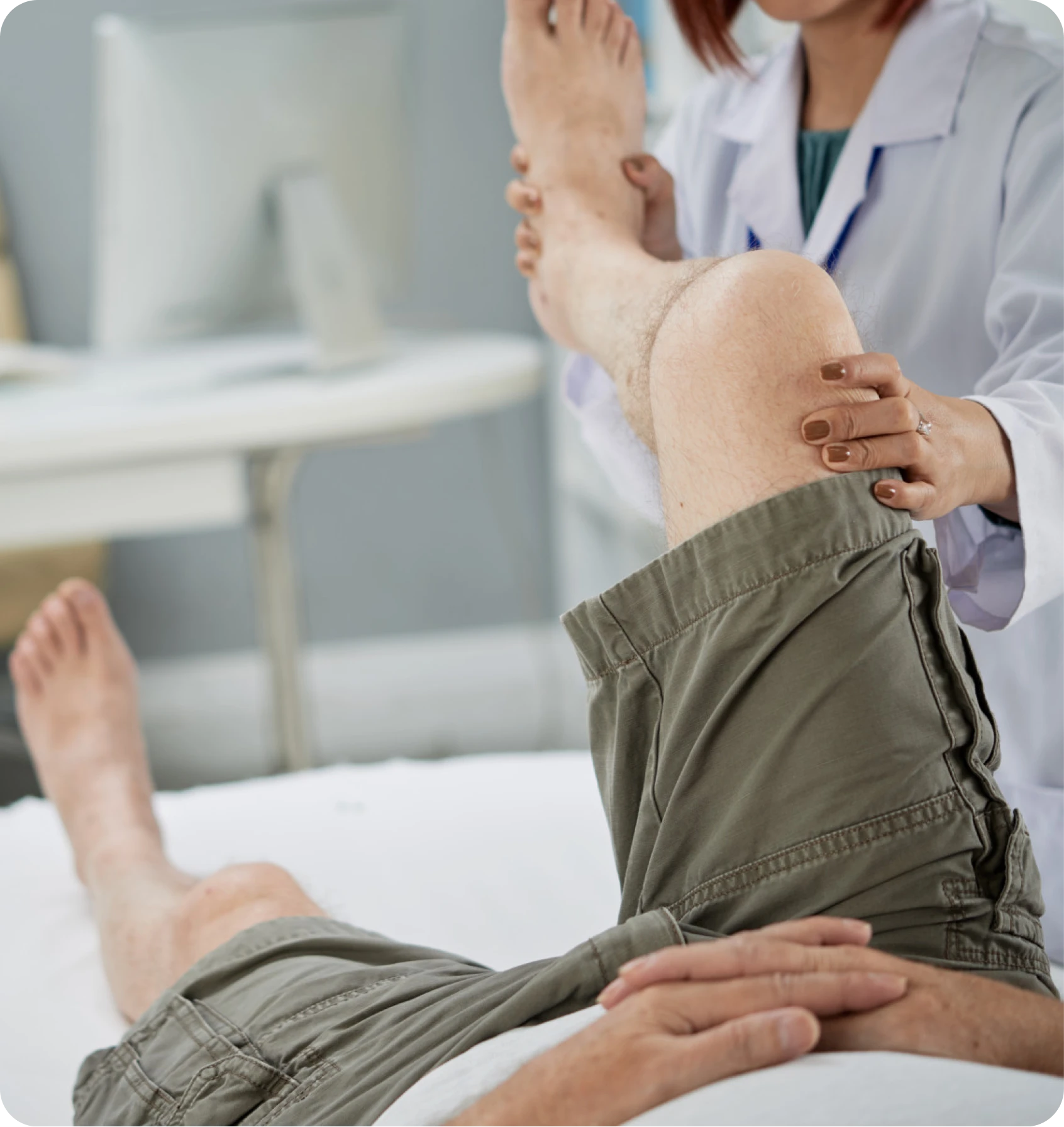 Clinician examining a patient’s lower leg and knee on an exam table