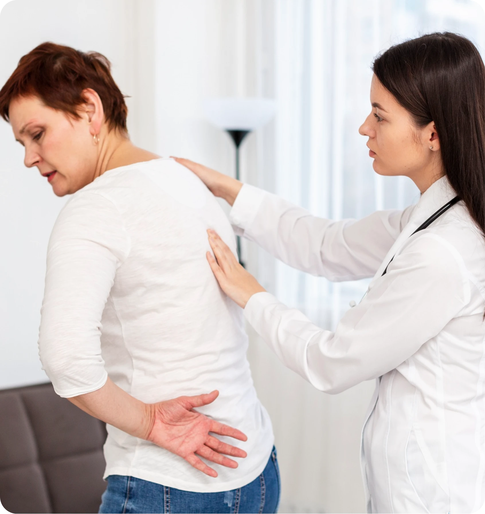 Clinician examining a woman who is holding her lower back