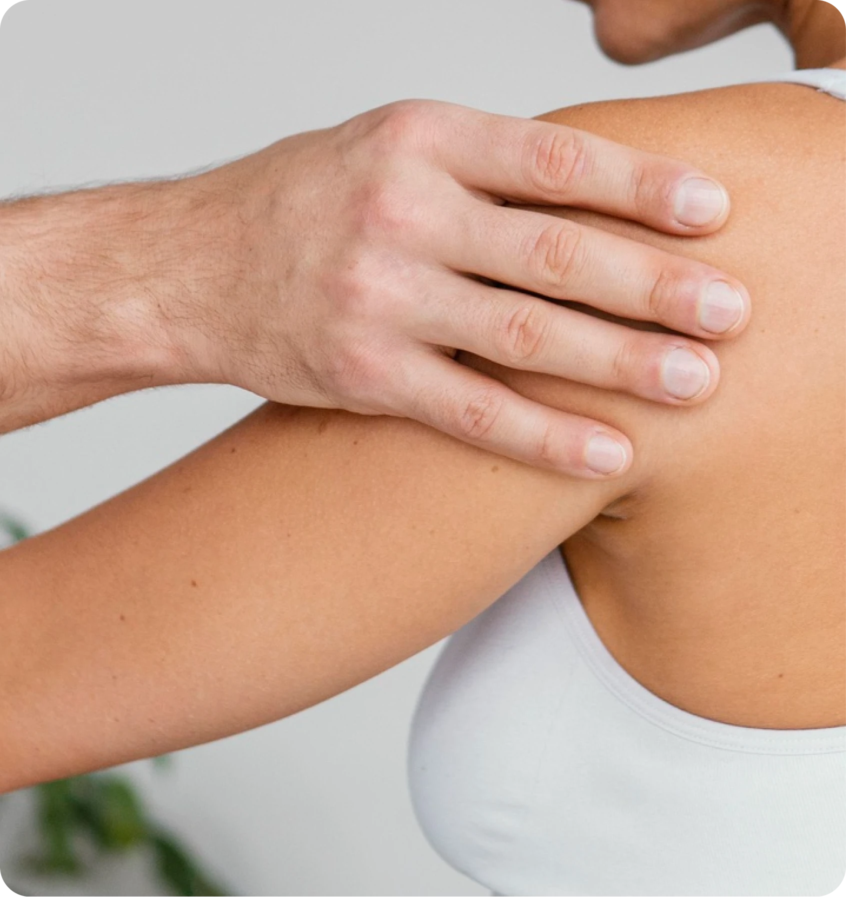 Close-up of a clinician’s hand examining a patient’s shoulder