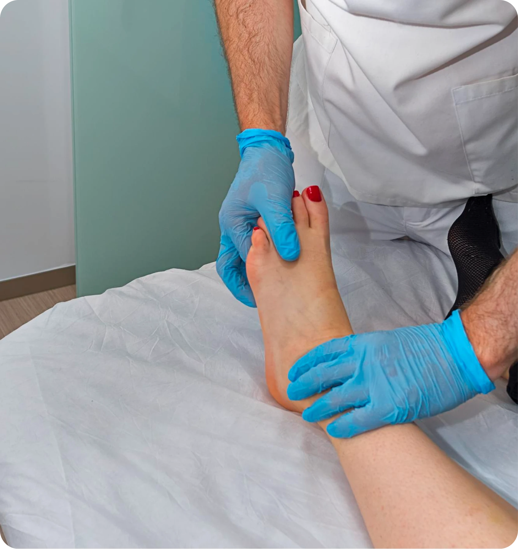 Gloved clinician examining a patient’s ankle and foot