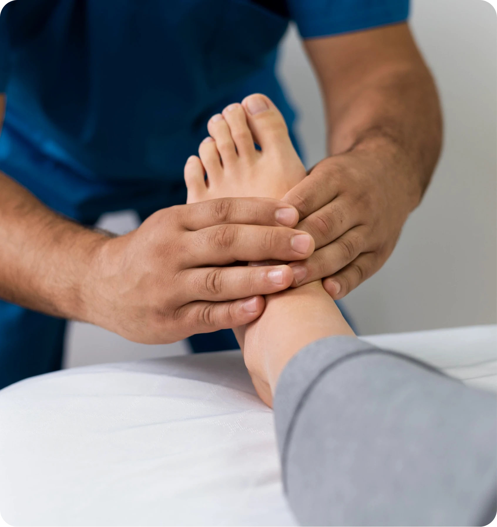 Clinician examining a patient’s ankle on an exam table